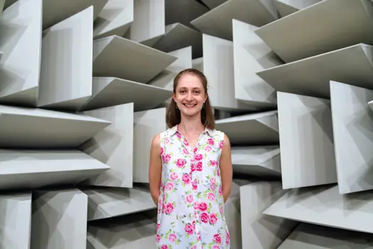 Lucy Richardson, female noise and acoustics engineer, smiles at camera in anechoic chamber