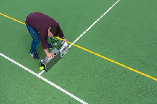 Male sports engineer tests tennis equipment on a tennis court