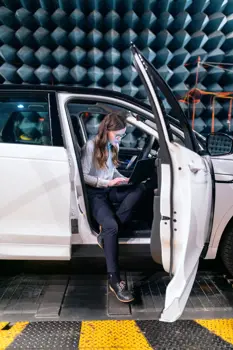 Female electronics and quality engineer with JLR vehicle in sound testing anechoic chamber