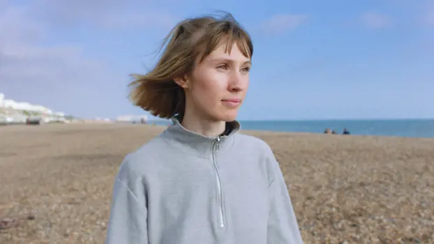  Female product designer standing on windy pebble beach