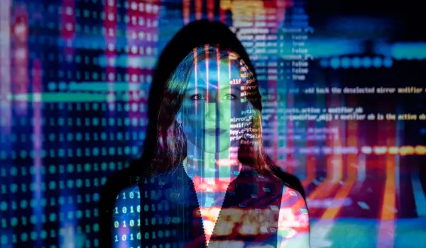 Female software engineer stands with code projected on a screen