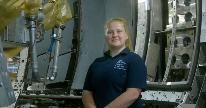 Charlotte Wilkes, female apprentice mechanical engineer smiling in workshop environment