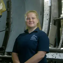 Charlotte Wilkes, female apprentice mechanical engineer smiling in workshop environment