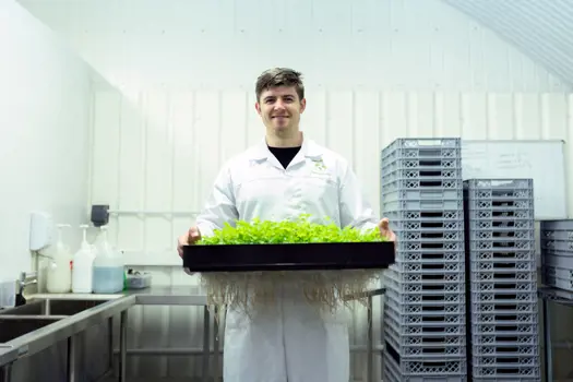 Male design engineer smiles at the camera while holding freshly grown lettuce