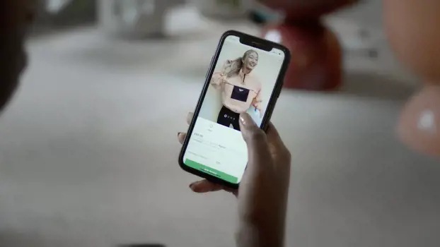Hand holding a mobile phone showing a fashion website