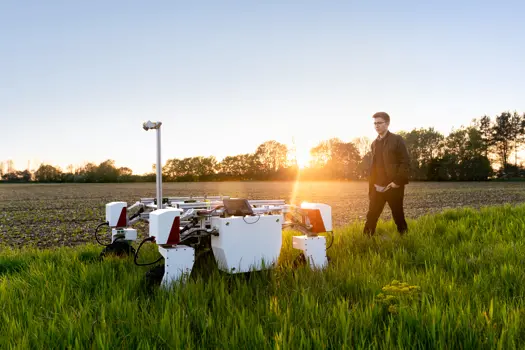  Male mechanical engineer with sustainable agricultural robot in field 