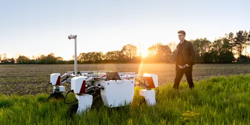  Male mechanical engineer with sustainable agricultural robot in field 