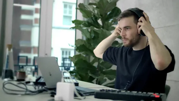 Male software engineer puts on headphones to code music applications