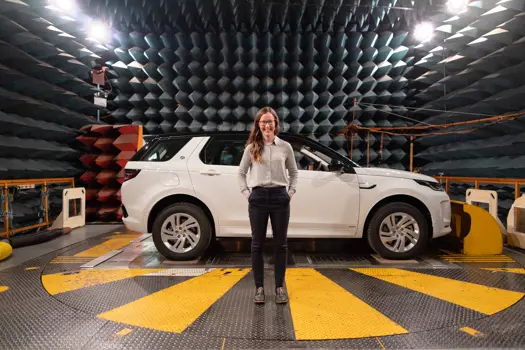 Female electronics and quality engineer stands with JLR vehicle in sound testing anechoic chamber