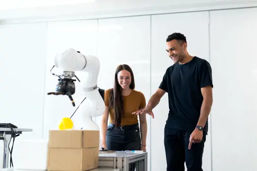 Male and female mechanical engineers work with robotic arm
